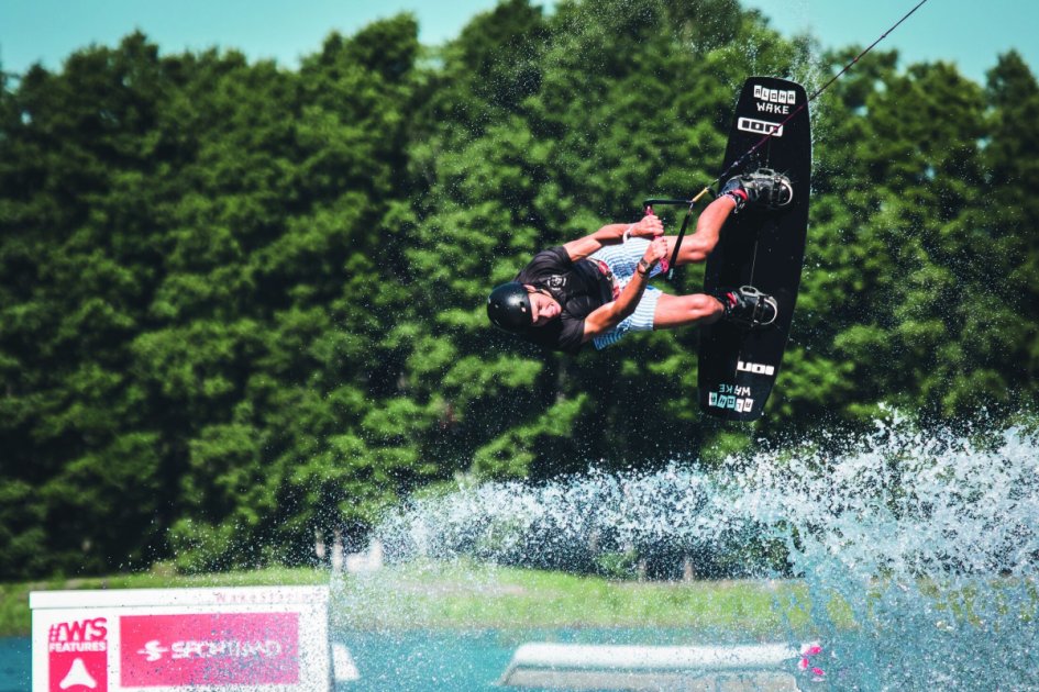 Wakeboarder catching air over a ramp obstacle on the cable park water at Pidula Wakepark